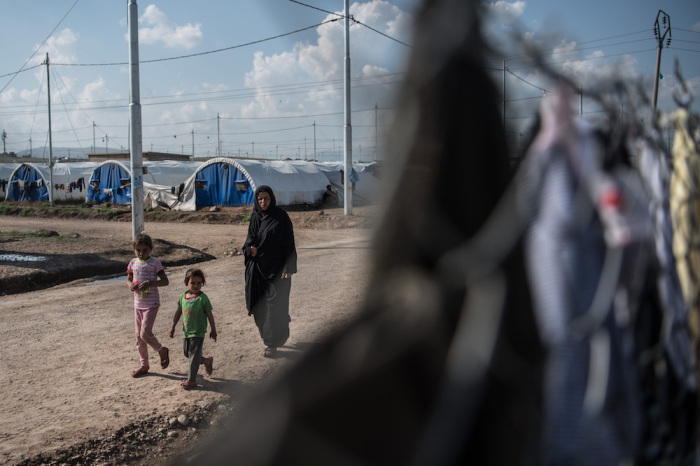 A woman and children walk through Khazir refugee camp on April 15, 2017 near Mosul, Iraq.