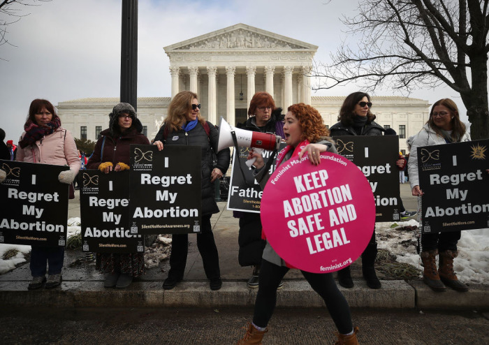 Pro-lifers stand in a line behind an abortion activist with a bullhorn.