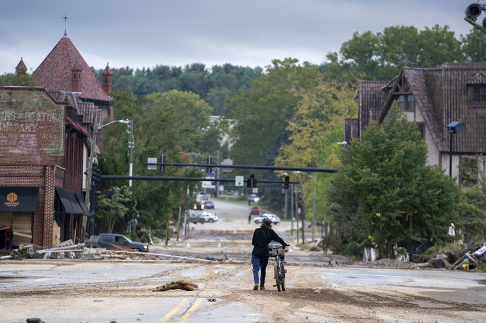 A person inspects the Biltmore Village with bicycle in the aftermath of Hurricane Helene on Sept. 28, 2024, in Asheville, North Carolina.