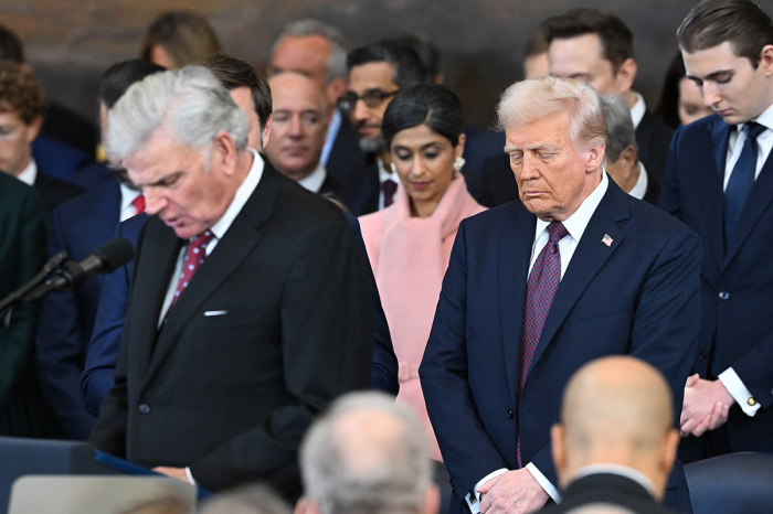 U.S. President-elect Donald Trump (C) bows his head as evangelist and president of Samaritan's Purse, Franklin Graham, delivers an invocation during the inauguration ceremony before Trump is sworn in as the 47th U.S. President in the U.S. Capitol Rotunda in Washington, D.C., on Jan. 20, 2025.